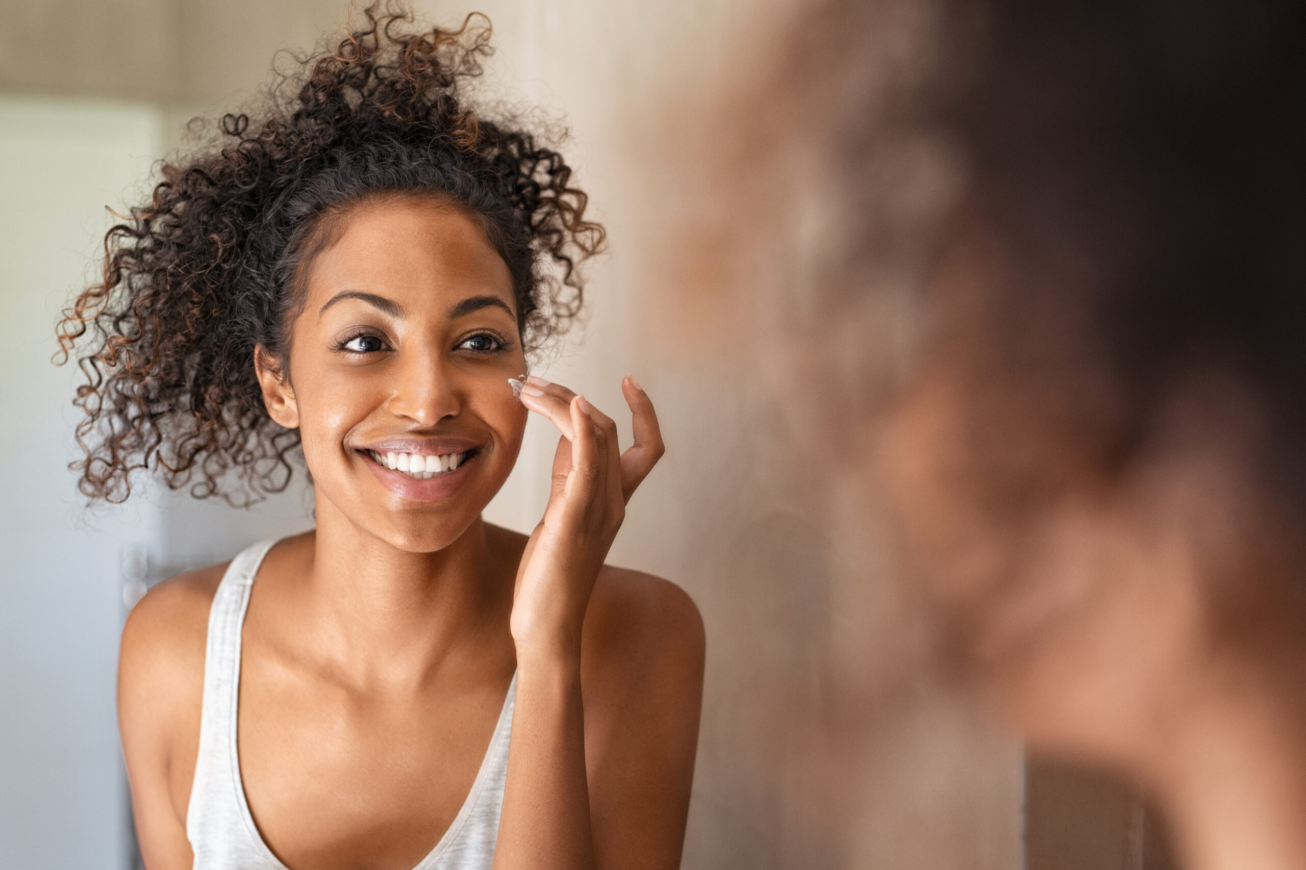 woman applying cream before mirror