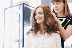 smiling woman while hairdresser does her hair