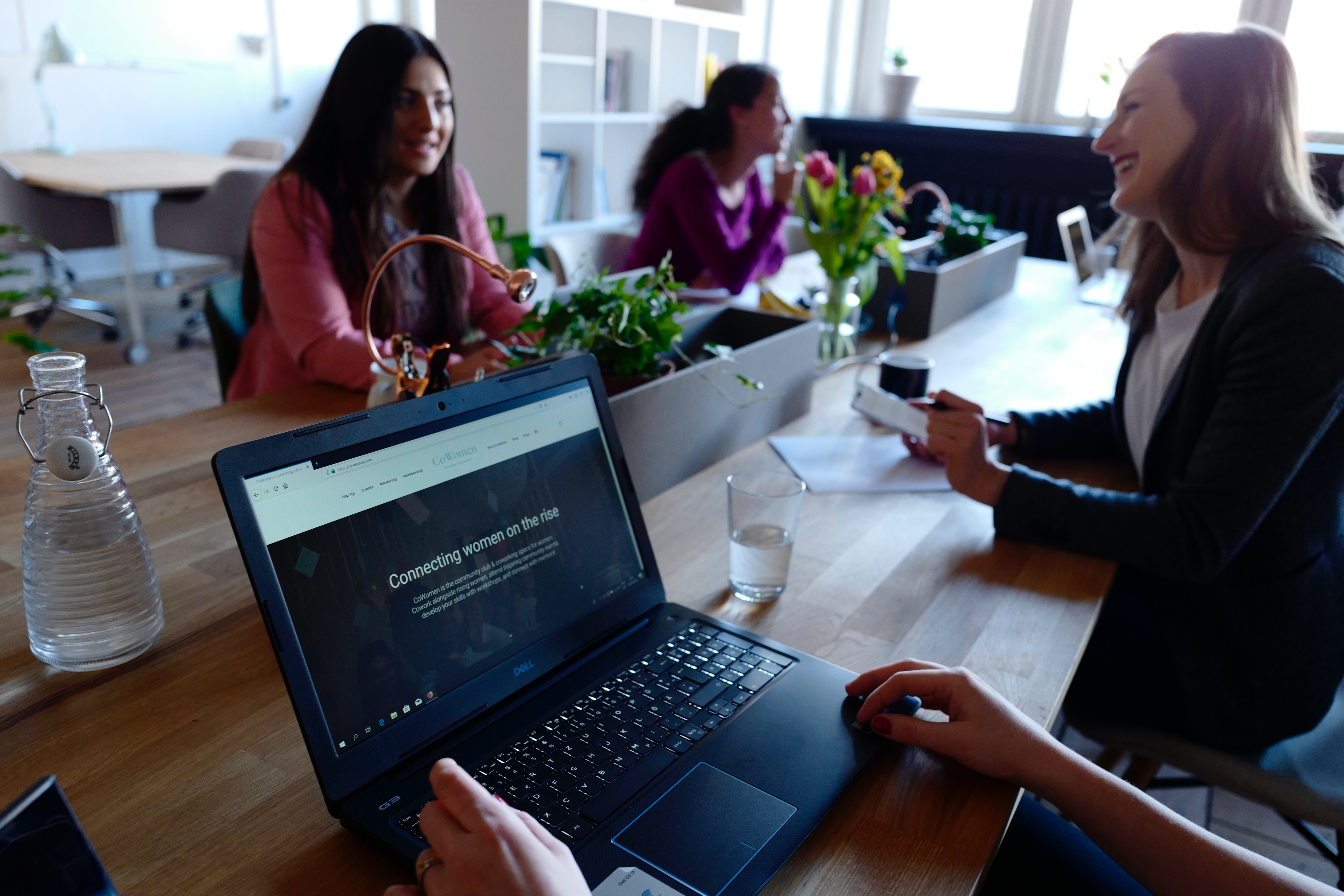 women talking at a table with laptops out