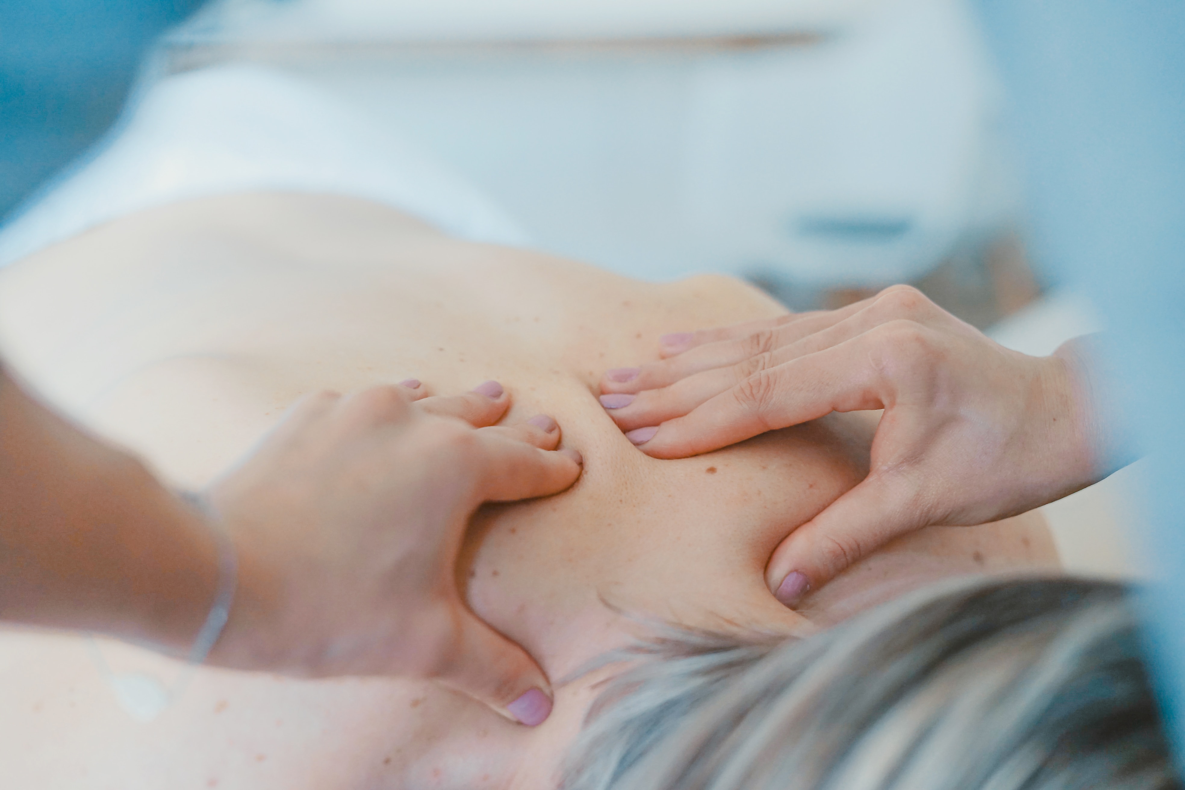 woman's hands massaging someones back at a spa