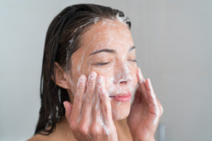 woman applying facial cleanser