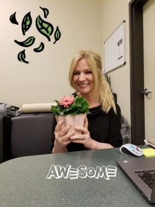 Evergreen employee "Sonya" holding potted flower and smiling