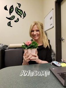 Evergreen employee "Sonya" holding potted flower and smiling