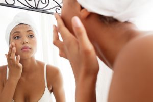 woman looking in mirror and touching face