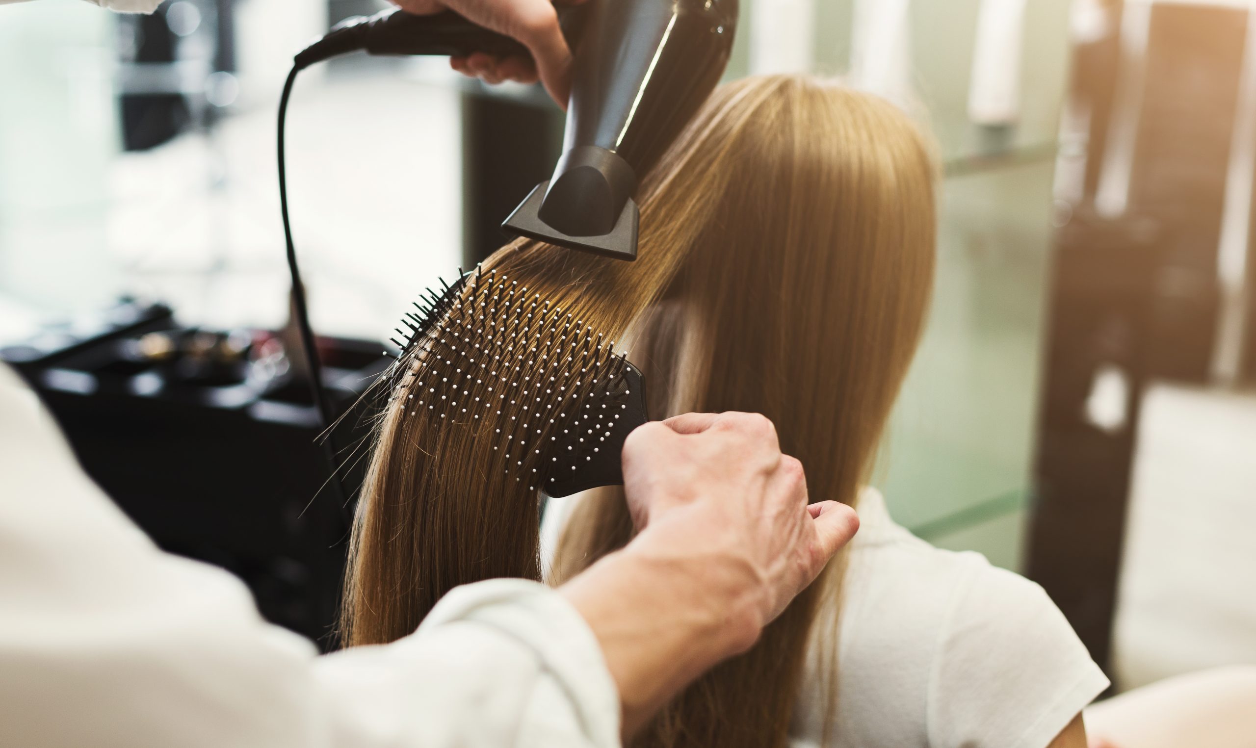 Professional hair stylist using hair dryer