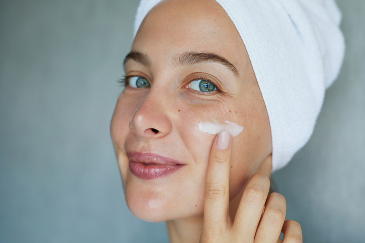 woman in bathrobe applying cream