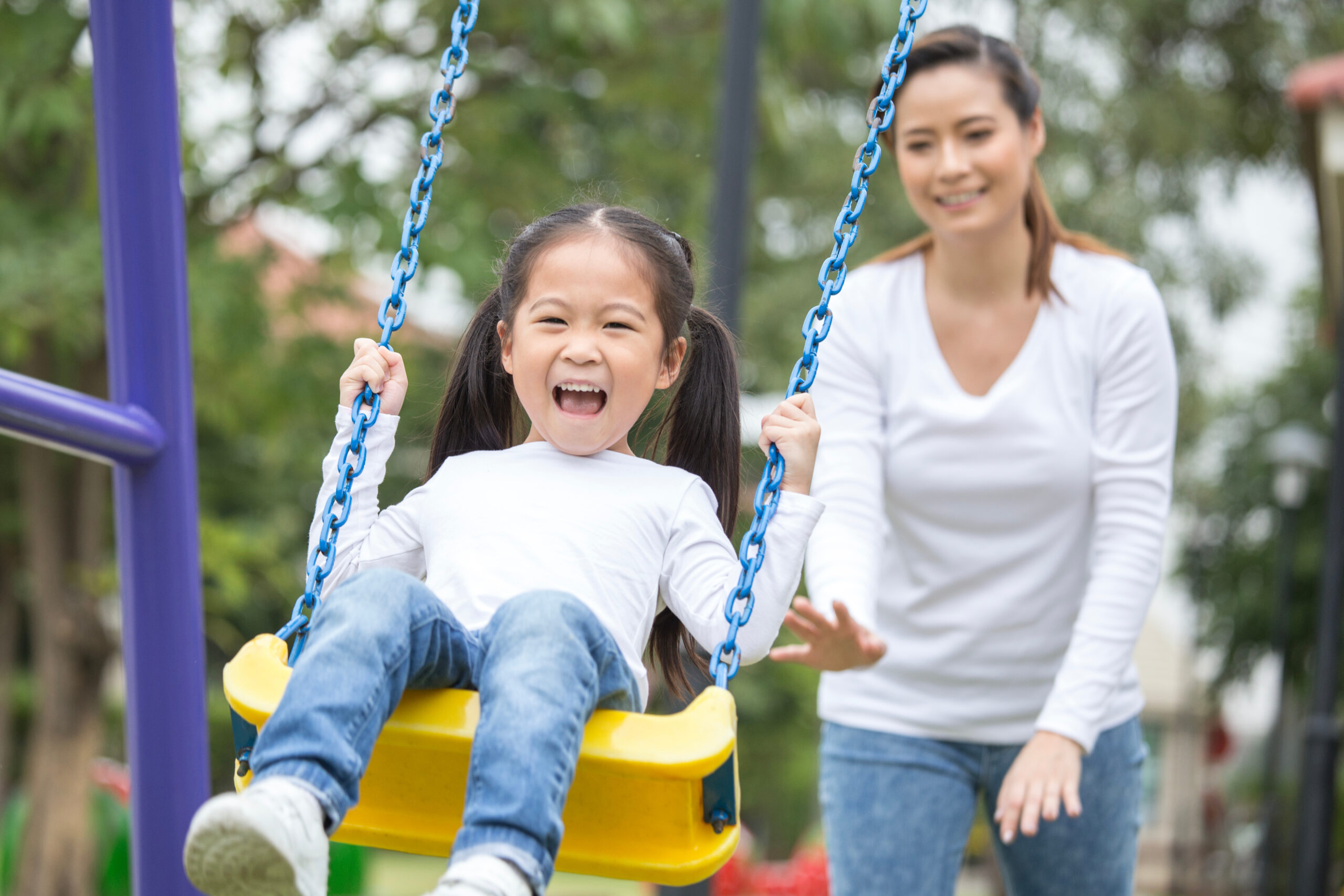 mother pushing daughter on swing