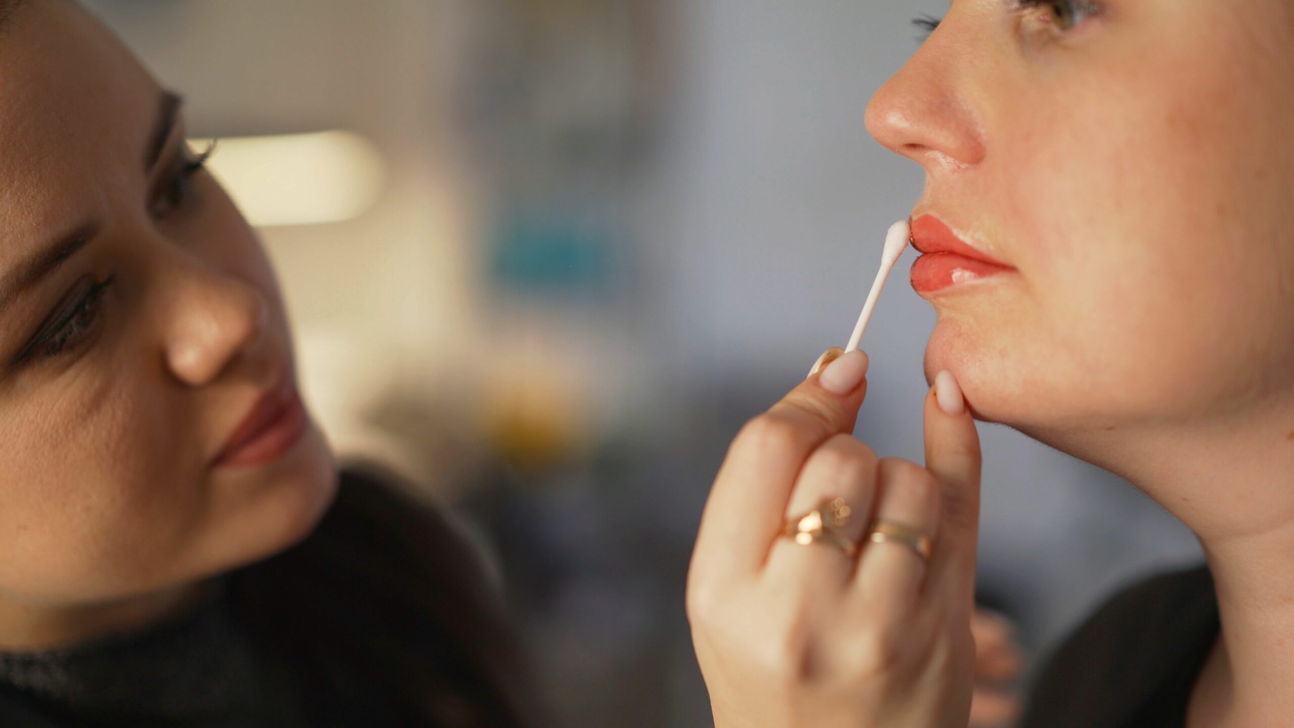 makeup artist applying lip gloss