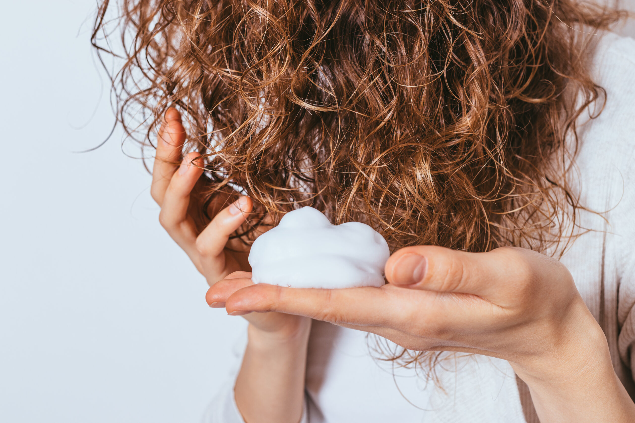 girl applying mousse to hair